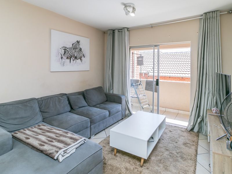 A comfortable living room featuring tiled flooring and sliding glass doors that provide direct access to a private balcony.