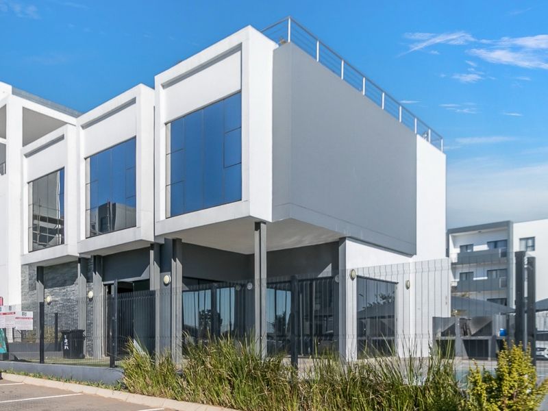Modern multi-story apartment building exterior featuring contemporary architectural design, large glass windows, and a rooftop terrace area.