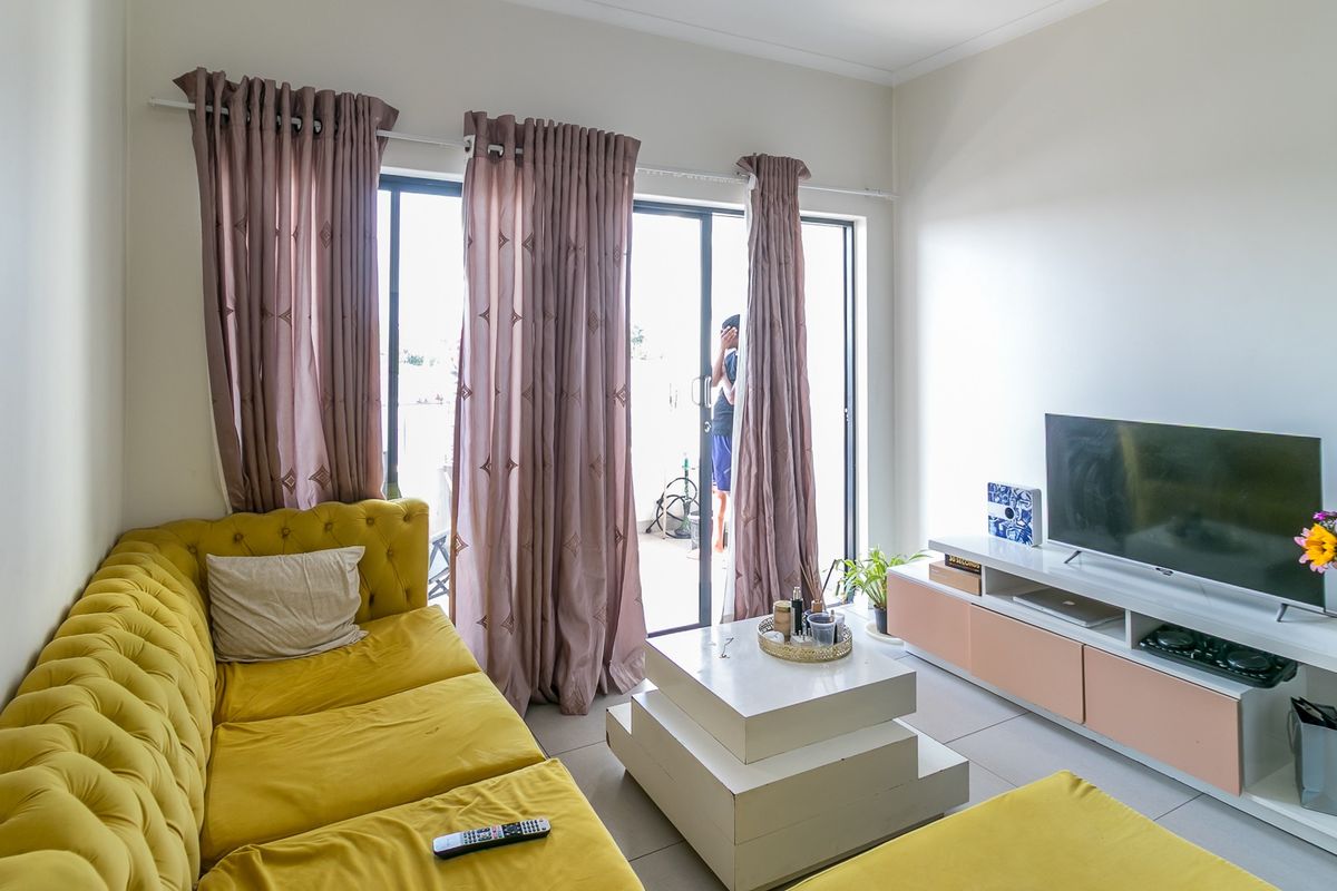 A bright living room featuring tiled flooring and a large sliding glass door providing access to an outdoor area.