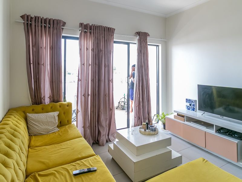 A bright living room featuring tiled flooring and a large sliding glass door providing access to an outdoor area.