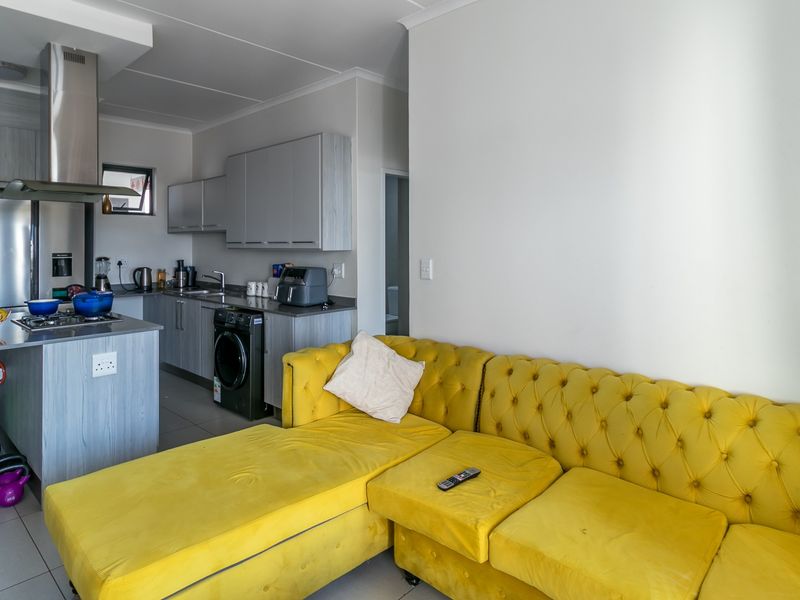 Modern open-plan living area featuring a contemporary kitchen with built-in cabinetry, stainless steel appliances, and a functional island, seamlessly connected to the living space.