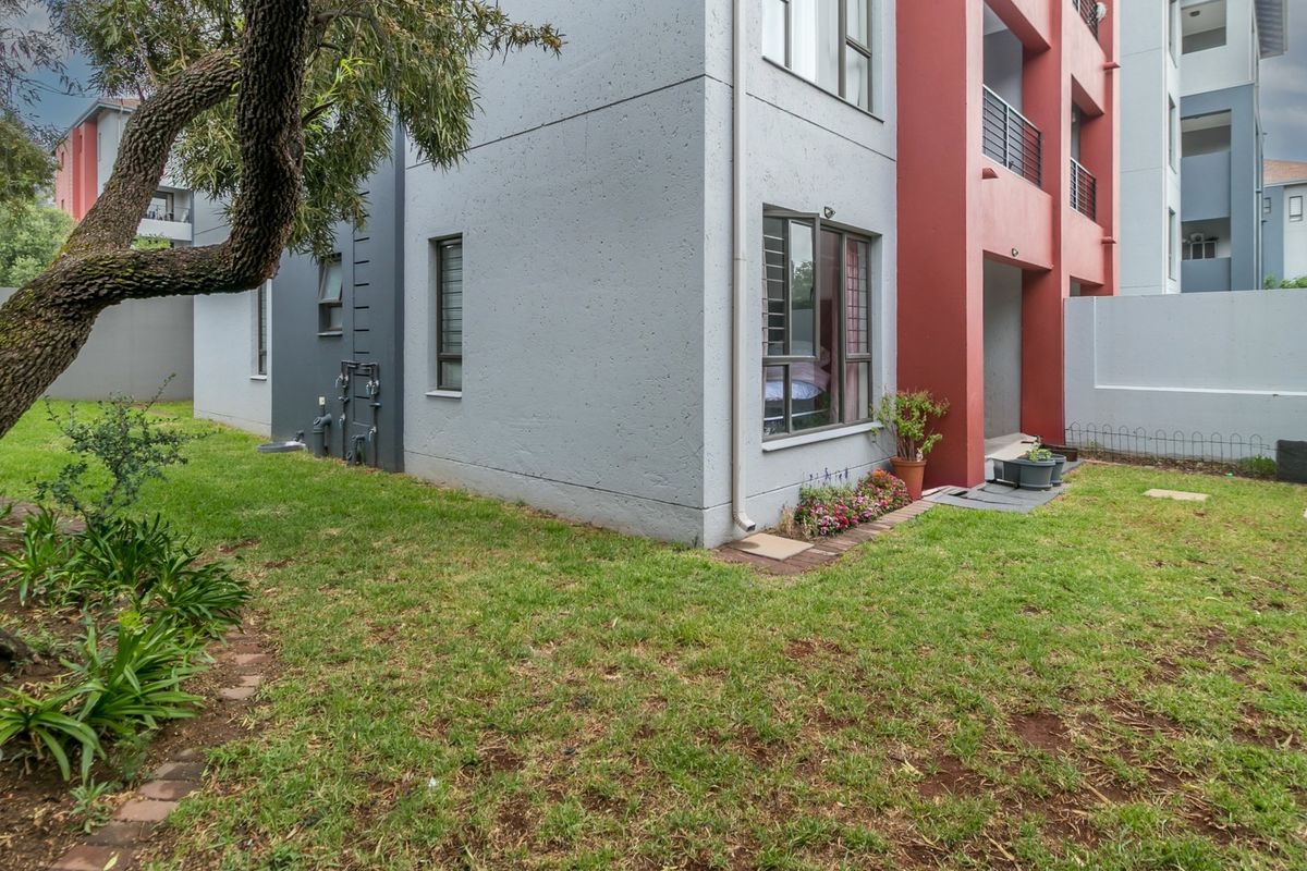 Rear view of the apartment building showing the exterior facade, private garden area, and ground floor access.