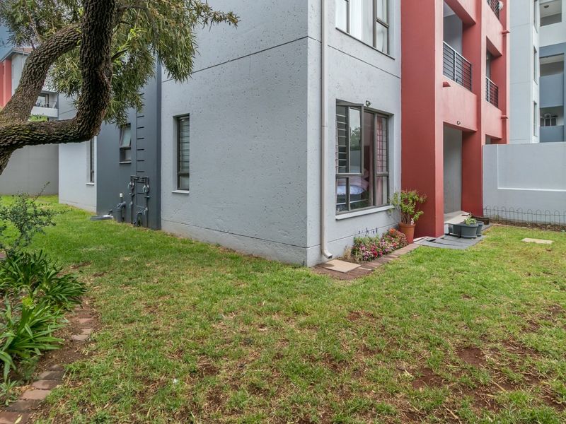Rear view of the apartment building showing the exterior facade, private garden area, and ground floor access.