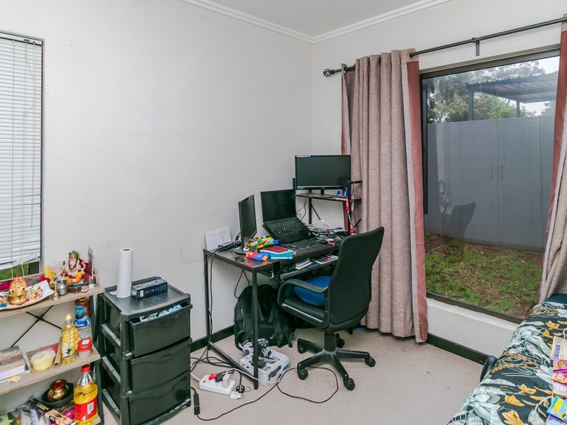 A bedroom featuring a large window with blinds and curtains, offering natural light and a view of the exterior area.