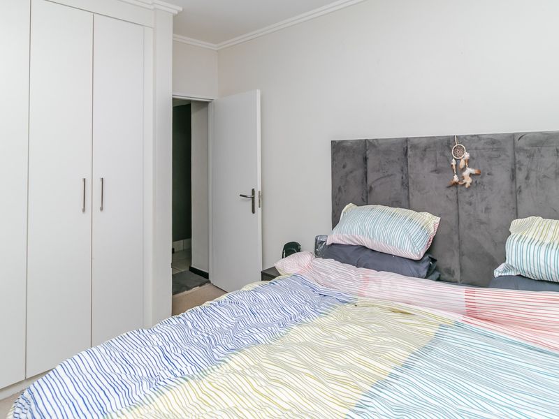 A well-maintained bedroom featuring a built-in wardrobe and a modern upholstered headboard, providing a clean and functional living space.