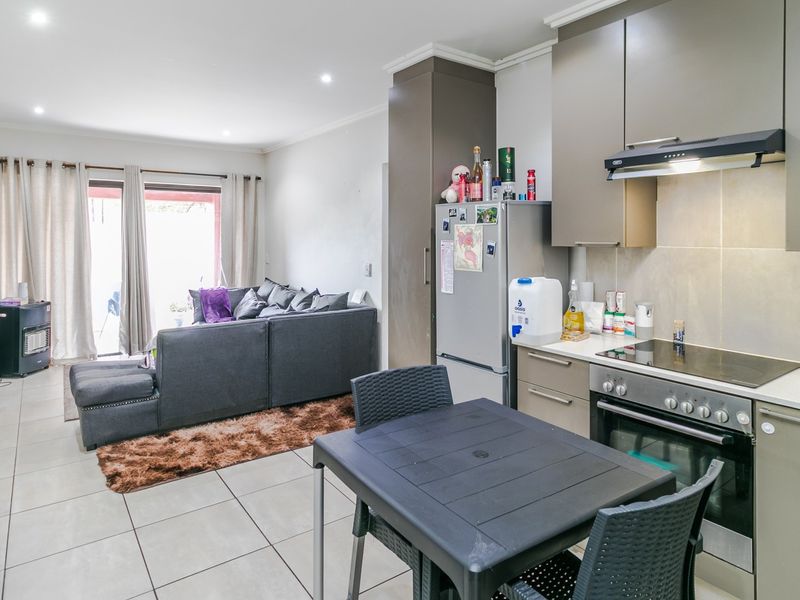 Open-plan living area featuring a modern kitchen with built-in appliances, tiled flooring, and direct access to an outdoor patio through sliding glass doors.