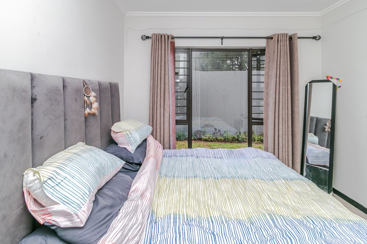 A bedroom featuring a sliding glass door with security bars, providing access to an outdoor area, finished with neutral walls and coving.