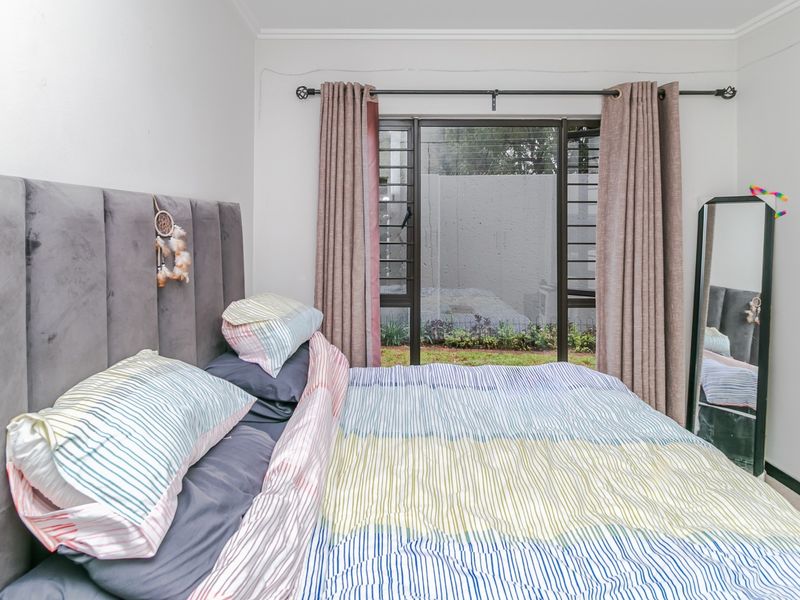 A bedroom featuring a sliding glass door with security bars, providing access to an outdoor area, finished with neutral walls and coving.