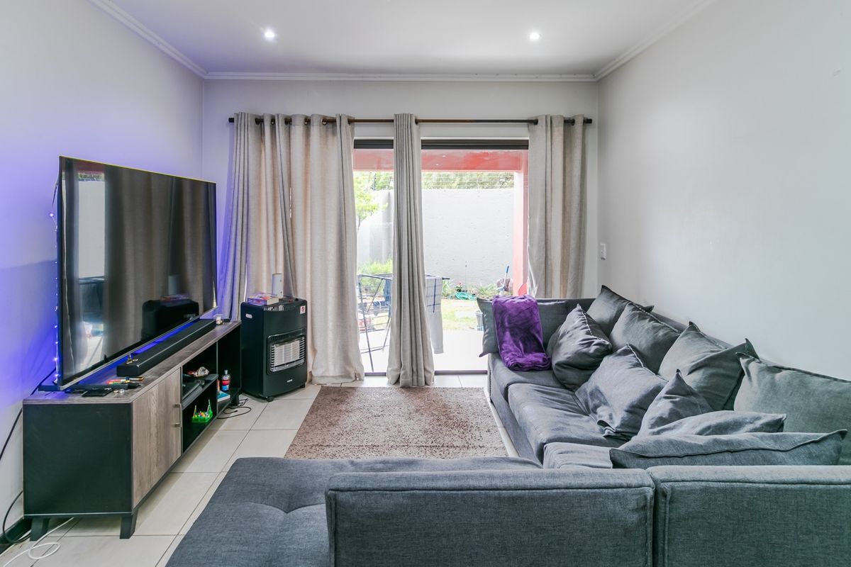 A living room featuring tiled flooring, recessed downlights, and a sliding glass door providing access to the outdoor area.