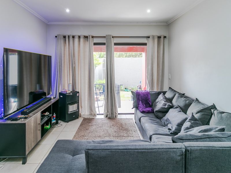 A living room featuring tiled flooring, recessed downlights, and a sliding glass door providing access to the outdoor area.