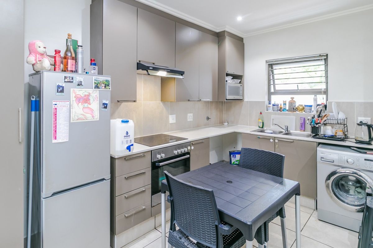Modern kitchen featuring sleek cabinetry, built-in oven and hob, extractor fan, and integrated laundry plumbing, offering a functional and well-organized cooking space.
