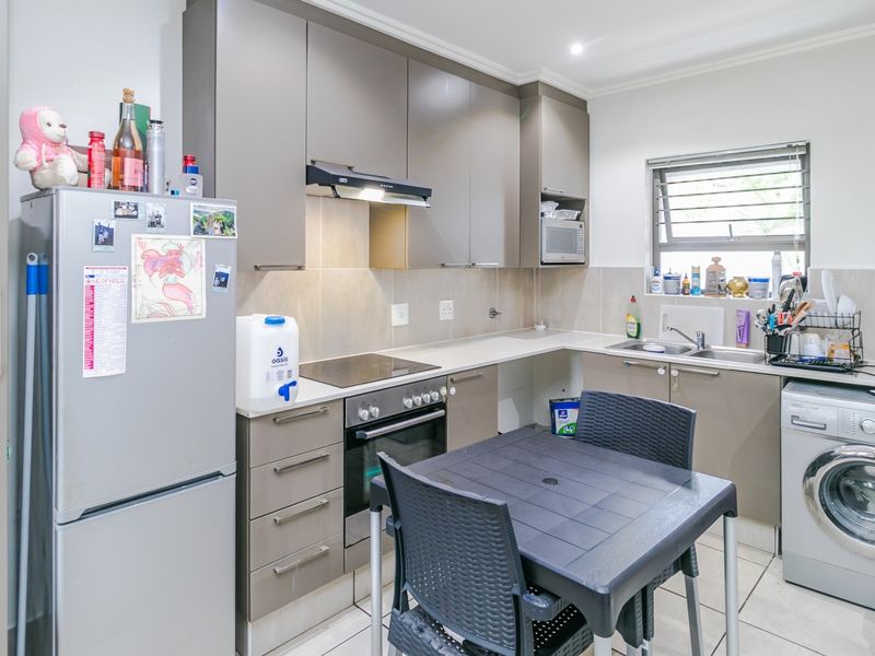 Modern kitchen featuring sleek cabinetry, built-in oven and hob, extractor fan, and integrated laundry plumbing, offering a functional and well-organized cooking space.