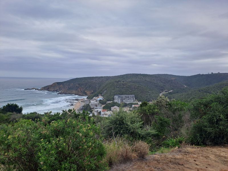 A scenic elevated view overlooking the coastline, surrounding hills, and nearby residential development.