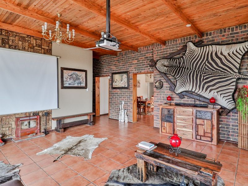 Spacious living area featuring exposed brick walls, a timber beam ceiling, tiled floors, and a built-in fireplace, currently set up as a home cinema.
