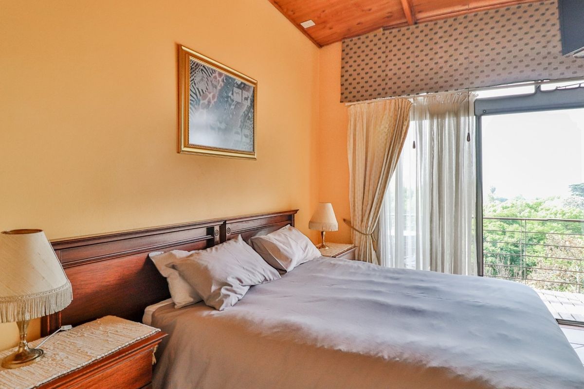 A bedroom featuring a timber vaulted ceiling and direct access to a balcony through sliding glass doors.