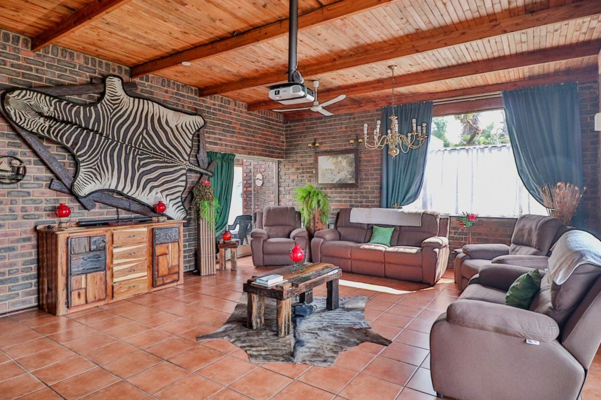 Spacious living room featuring exposed brick walls, a high timber-beamed ceiling, and durable ceramic tile flooring, creating a rustic and warm atmosphere.