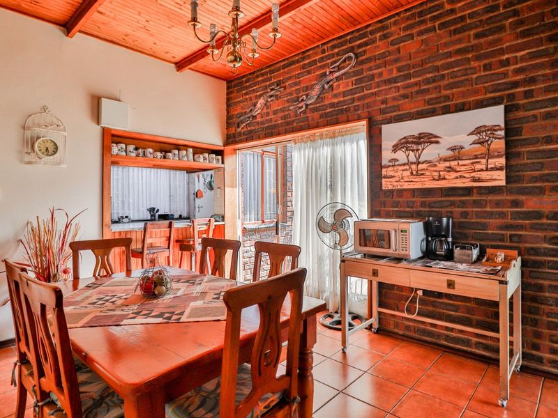 Dining room featuring exposed brick walls, timber ceiling, ceramic floor tiles, and direct access to the outdoor area through a sliding glass door.