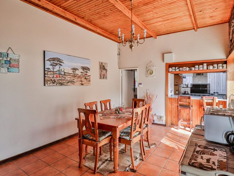 Open plan dining area featuring a timber ceiling, terracotta floor tiles, and a serving hatch connecting to the kitchen.