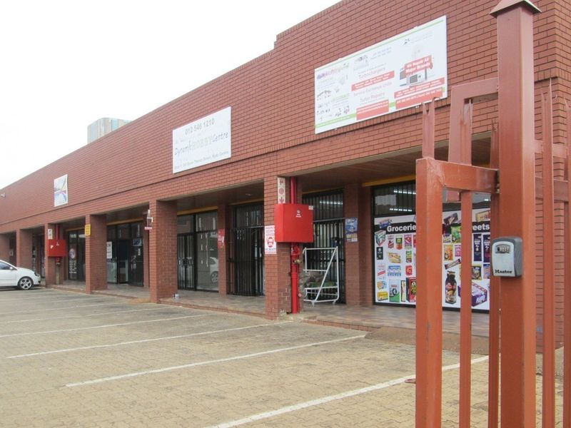 Front exterior view of a commercial office and retail strip center featuring brick construction, paved parking, and secure glass storefront entrances.
