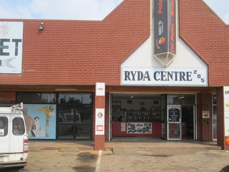 Front elevation of Ryda Centre, a commercial office and retail property featuring brick construction, prominent signage, and glass storefront access.