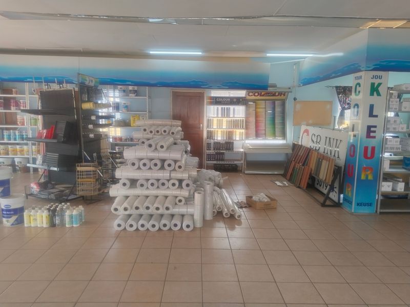 A commercial office or retail space featuring tiled flooring, built-in shelving, and overhead fluorescent lighting, currently utilized for product storage and display.