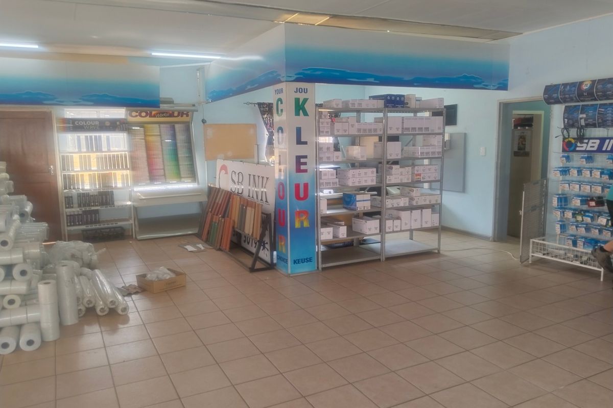 A functional commercial office or retail space featuring tiled flooring, suspended ceilings, and integrated lighting, currently utilized for product display and storage.
