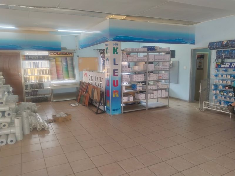 A functional commercial office or retail space featuring tiled flooring, suspended ceilings, and integrated lighting, currently utilized for product display and storage.