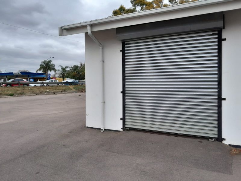 Exterior view of a commercial building featuring a secure metal roller shutter door and functional guttering system.