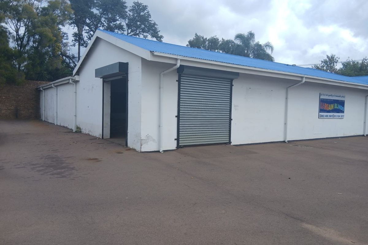 Commercial warehouse building featuring roller shutter doors, a metal roof, and paved exterior access area.