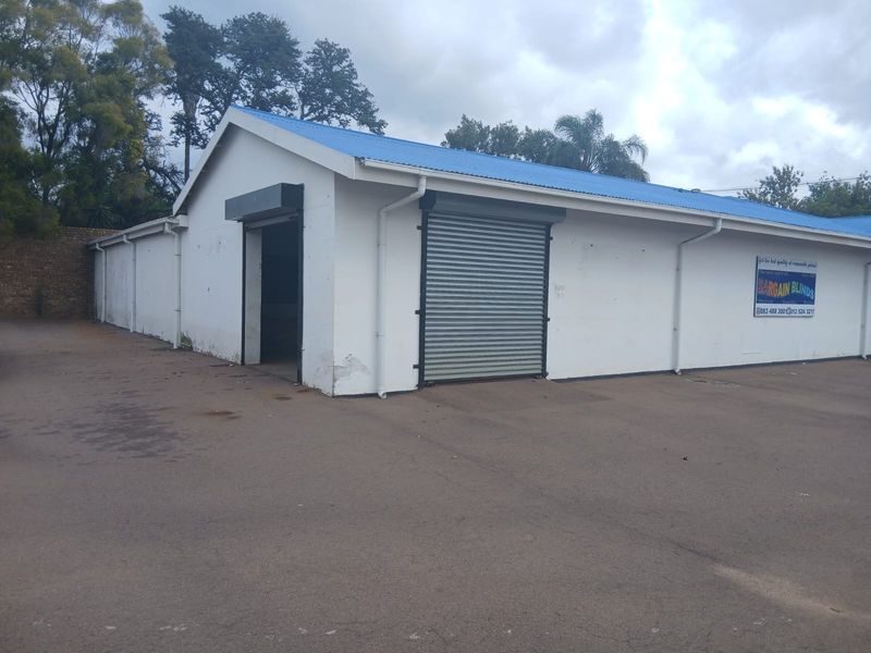 Commercial warehouse building featuring roller shutter doors, a metal roof, and paved exterior access area.
