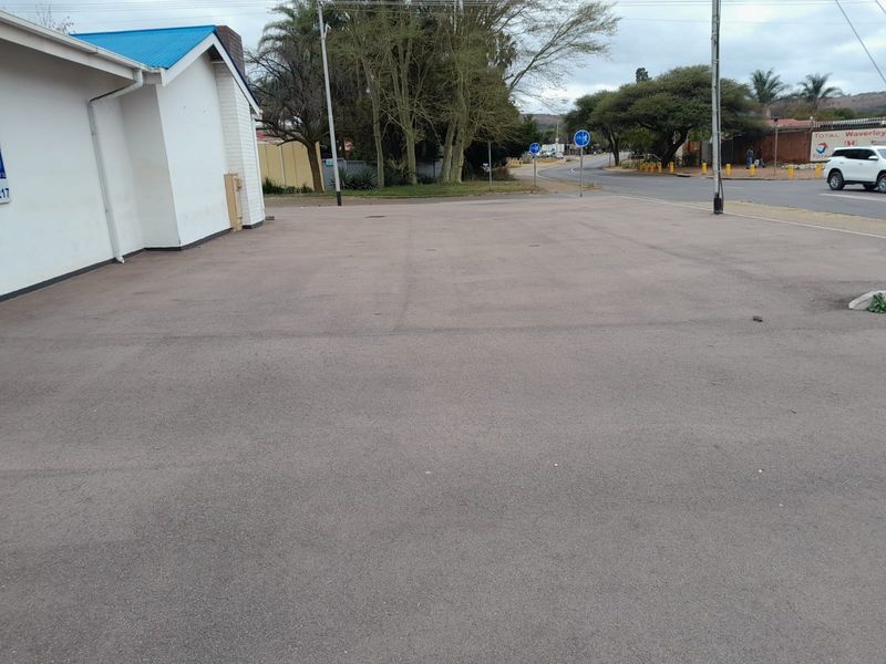 A paved asphalt parking area adjacent to a commercial building with a painted brick exterior and blue metal roof.