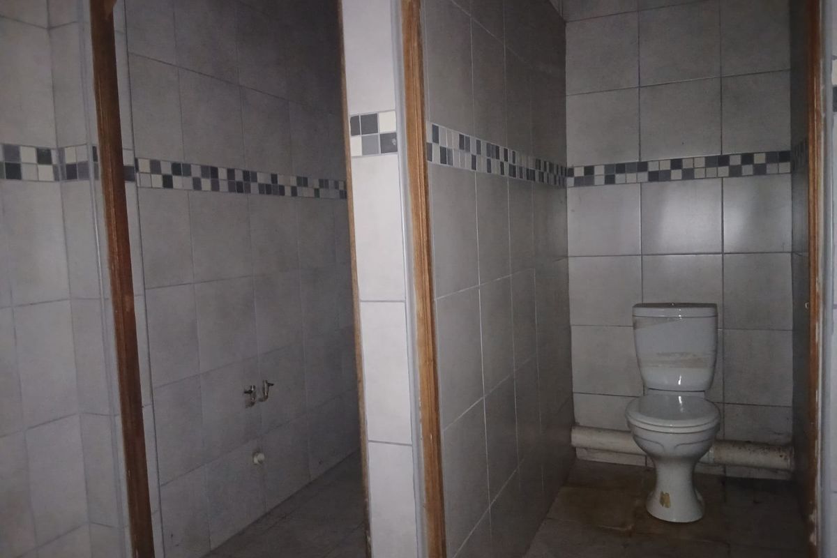 A basic, dated bathroom facility featuring tiled walls and flooring, currently in need of maintenance and cosmetic updates.