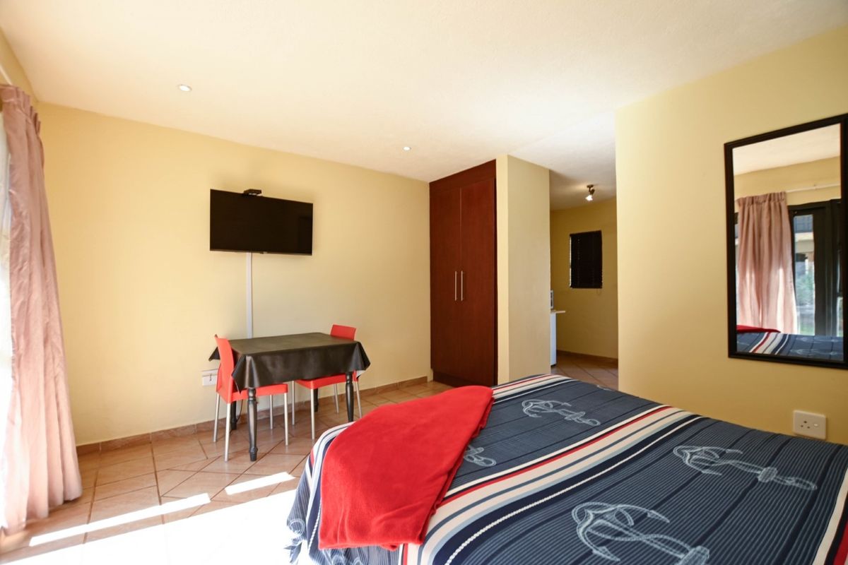A bedroom featuring tiled flooring, recessed downlighting, and a built-in wardrobe, with an adjacent view into a secondary space.