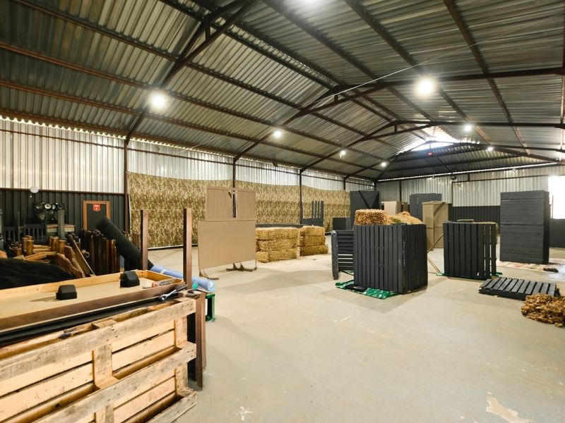 Large indoor sports facility featuring a high corrugated metal roof, exposed steel trusses, and durable concrete flooring, currently set up for tactical activities.