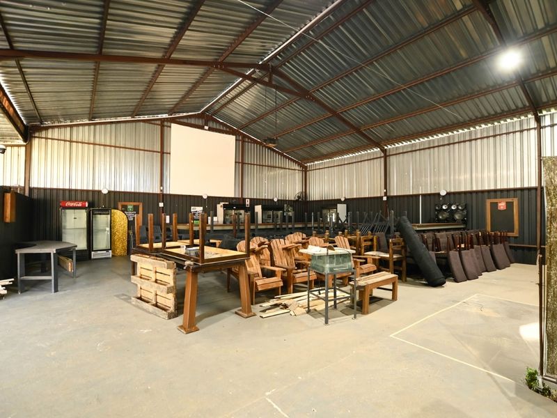 Spacious industrial-style clubhouse featuring high vaulted ceilings with exposed steel trusses, metal wall cladding, and a large open-plan layout suitable for events.