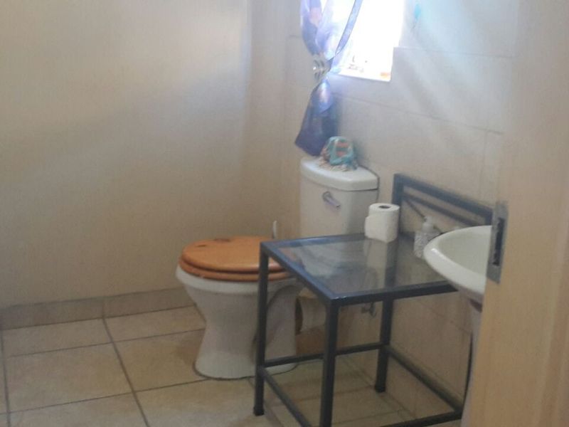 A functional bathroom featuring a standard toilet, wall-mounted washbasin, and tiled finishes throughout.