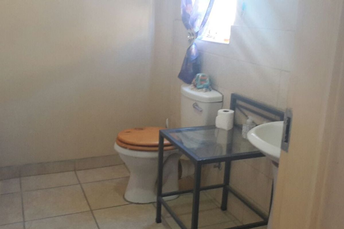 A functional bathroom featuring a standard toilet, wall-mounted washbasin, and tiled finishes throughout.
