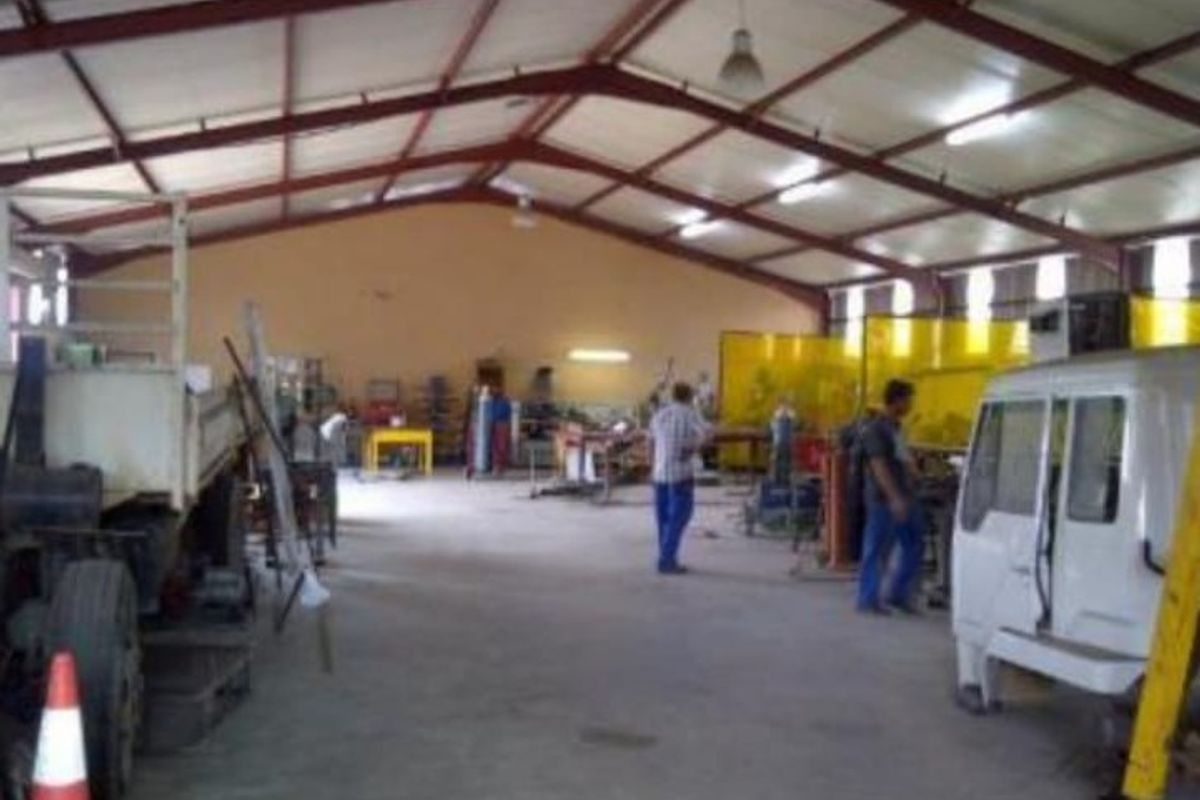 Spacious industrial workshop featuring an exposed steel portal frame, concrete flooring, and functional industrial lighting, suitable for various manufacturing or storage operations.
