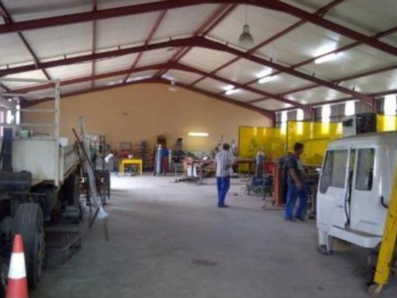 Spacious industrial workshop featuring an exposed steel portal frame, concrete flooring, and functional industrial lighting, suitable for various manufacturing or storage operations.