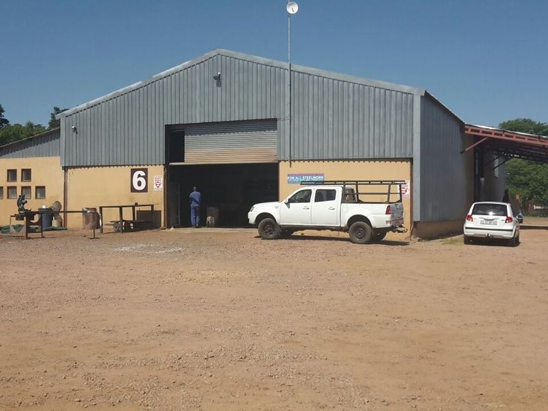 Front elevation of an industrial warehouse featuring a large roller shutter door, corrugated metal cladding, and a gabled roof structure.