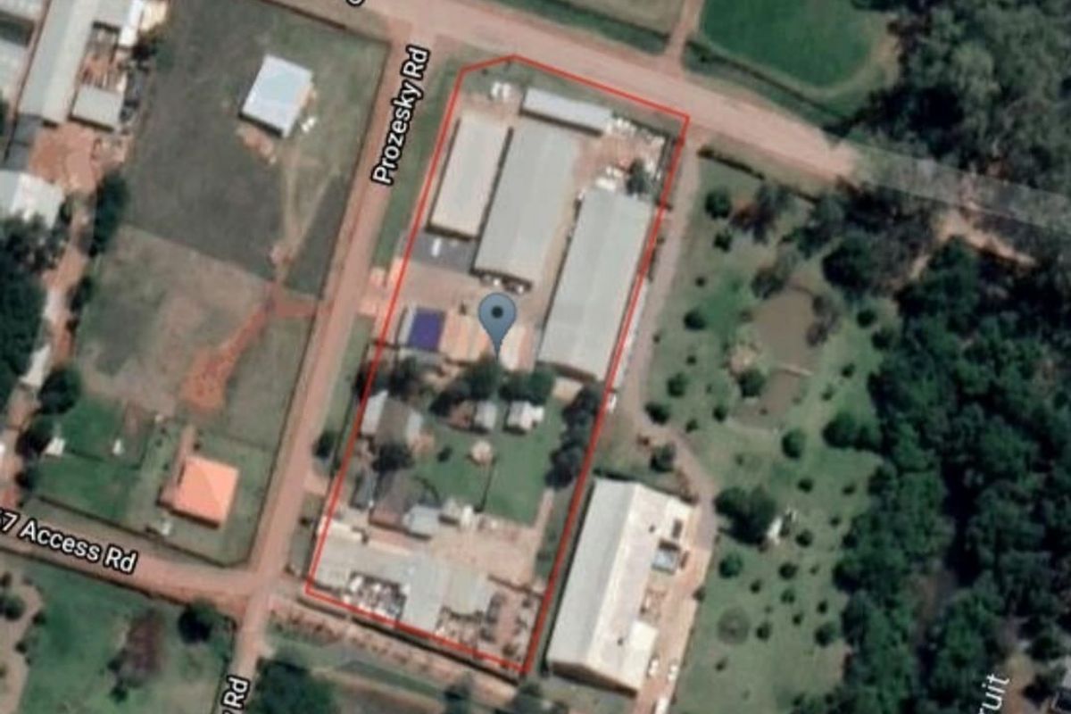 Aerial view of the retail property site showing multiple buildings, perimeter fencing, and surrounding road access.