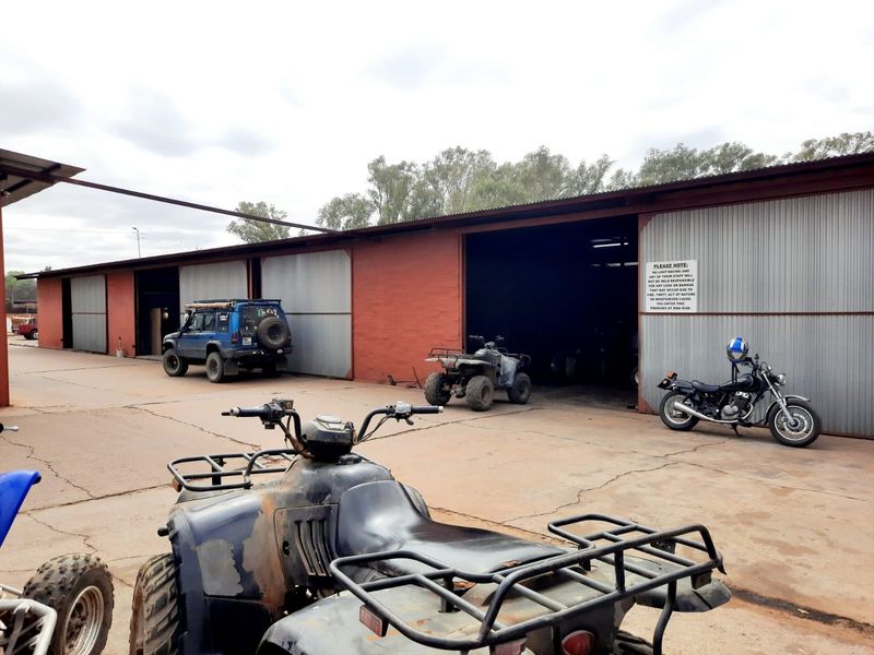 A large industrial-style garage facility featuring multiple bays with corrugated metal cladding and a concrete forecourt.