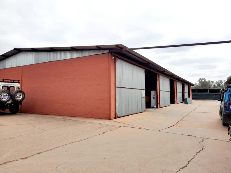Exterior view of a commercial warehouse or storage facility featuring large sliding corrugated metal doors and a concrete apron.