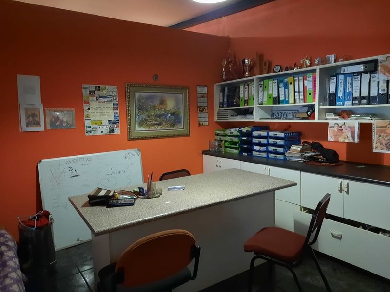 A functional office space featuring built-in cabinetry, ample storage shelving, and a central laminate work surface.