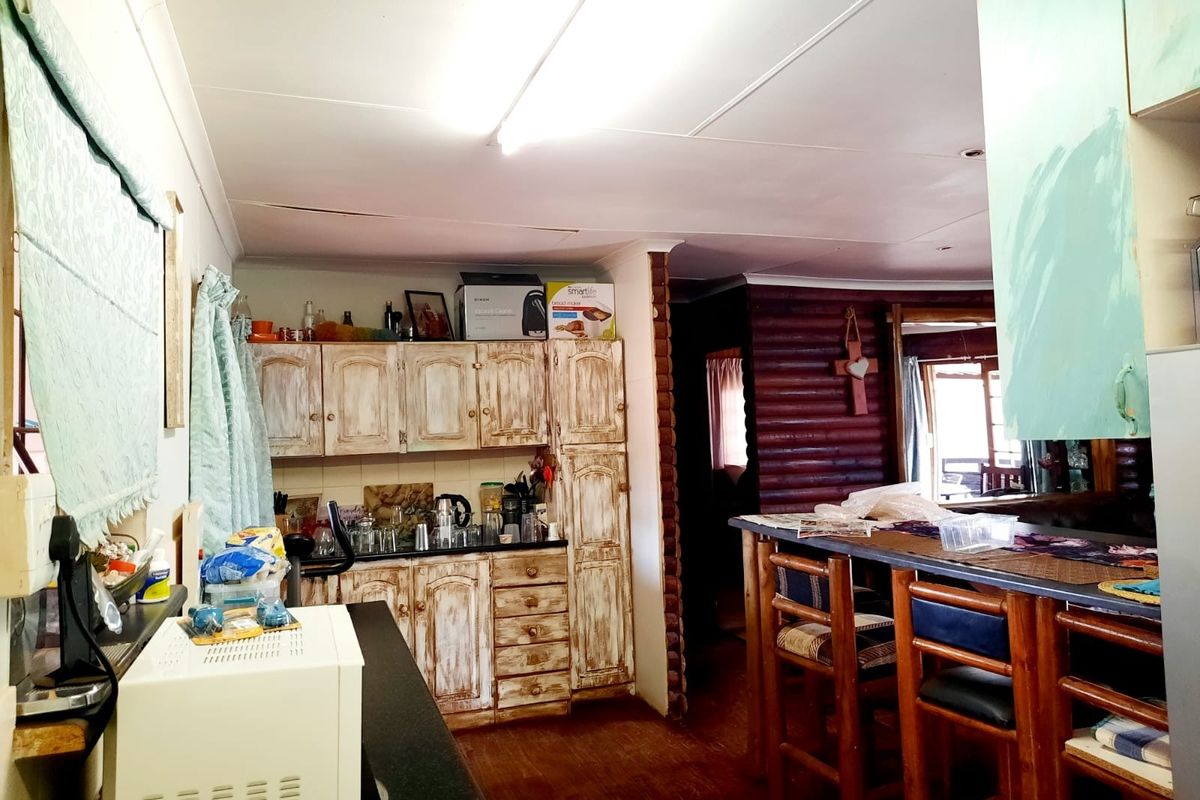 A rustic kitchen area featuring built-in cabinetry, a breakfast bar, and log wall detailing, requiring cosmetic updates to modernize the space.