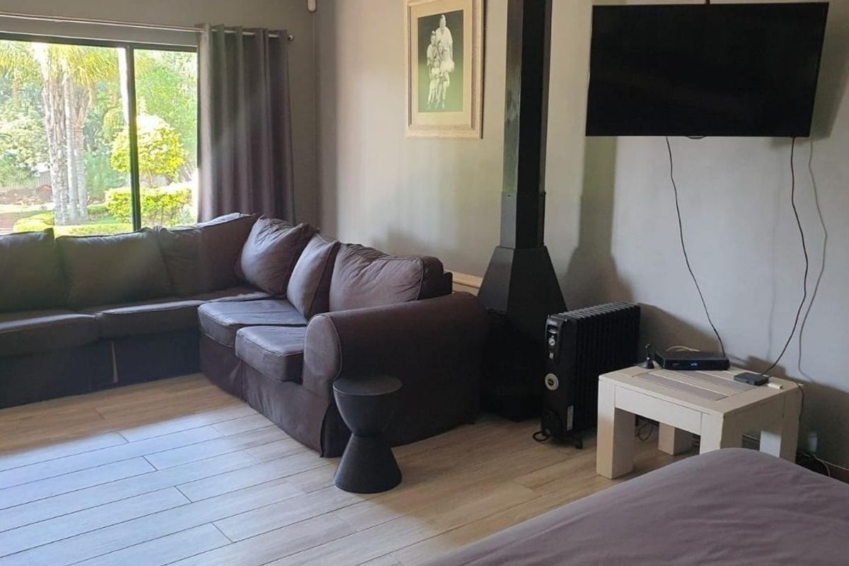 A comfortable living room featuring light-toned tiled flooring, a modern wood-burning fireplace, and large sliding glass doors providing natural light and garden views.
