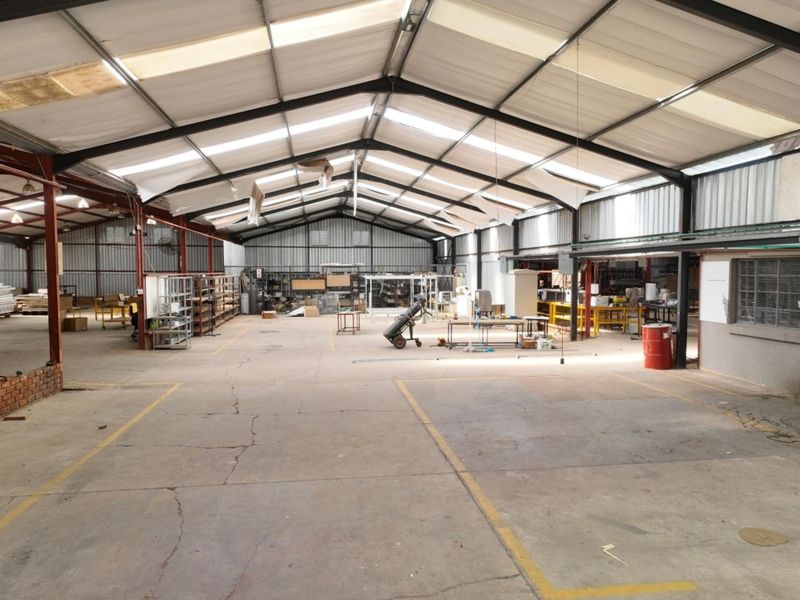 Large industrial utility space featuring a steel portal frame, concrete flooring, and translucent roof panels, suitable for workshop or storage use.