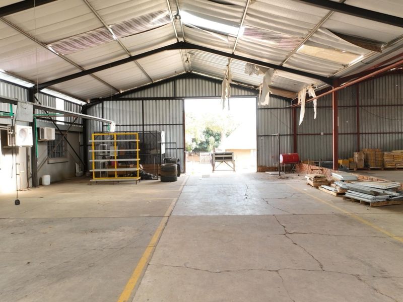 A large, open-plan utility or storage shed featuring a steel frame, corrugated metal roofing, and concrete flooring, suitable for workshop or agricultural storage use.