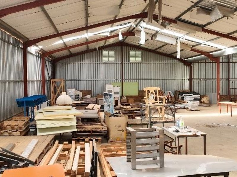 A large industrial-style utility space or barn featuring a steel portal frame, corrugated metal walls, and a concrete floor, suitable for storage or workshop use.