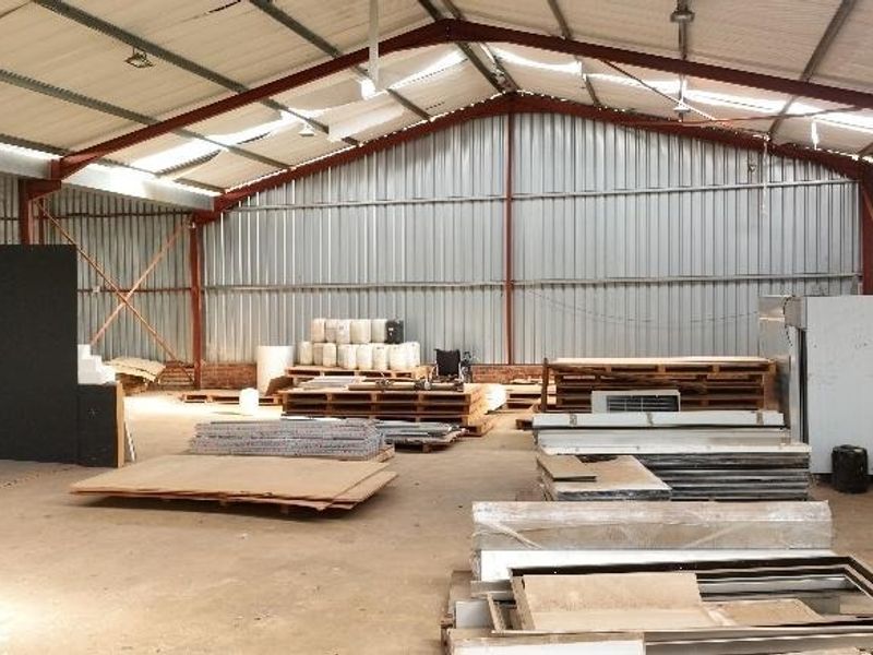 Spacious industrial utility shed featuring a steel portal frame, corrugated metal walls, and a concrete floor, suitable for storage or workshop use.